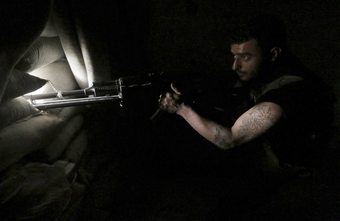 A rebel fighter takes position behind sandbags in Aleppo's Al-Ezaa neighbourhood